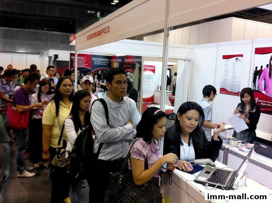 People queuing at a recruitment agency booth during a job fair.
