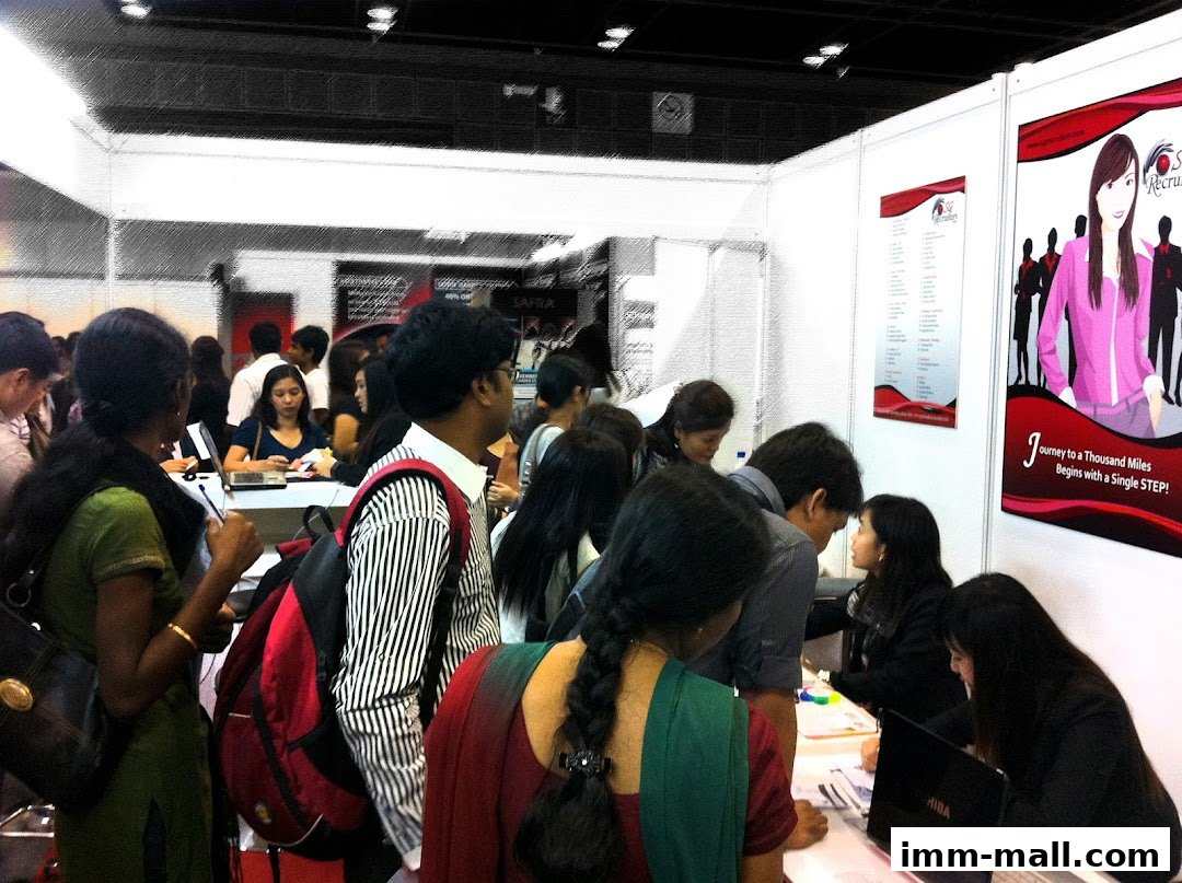 People gathered at a recruitment fair, interacting with a booth.