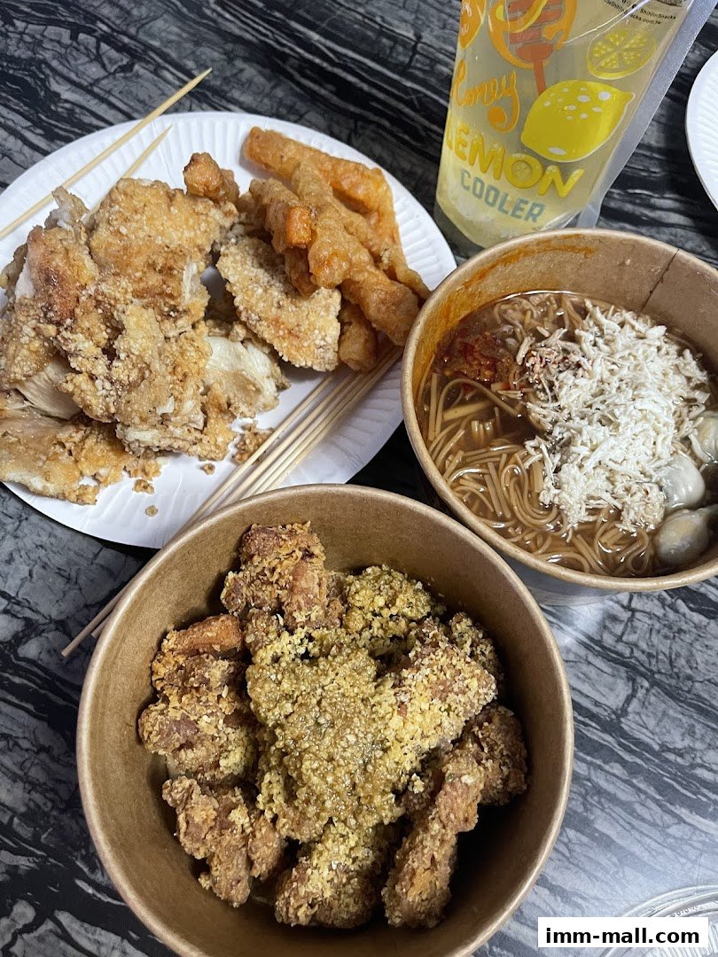 A spread of Taiwanese street food including fried chicken, crispy pork, and noodles with a lemon cooler drink.