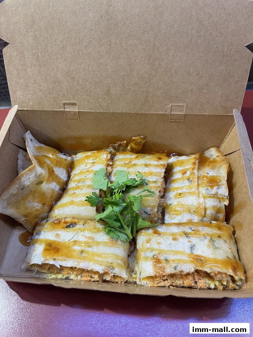 A close-up of Taiwanese street food, likely a savory crepe, served in a cardboard box.
