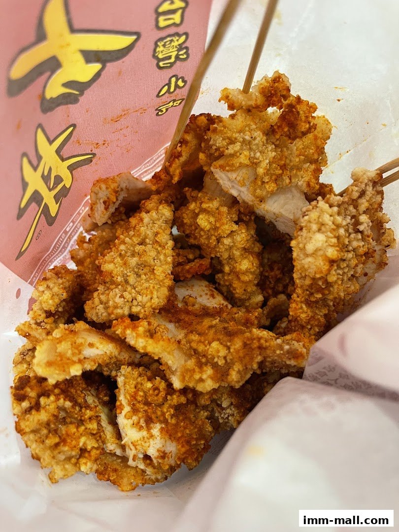 A close-up shot of crispy, seasoned fried chicken pieces on skewers from Shihlin Taiwan Street Snacks.
