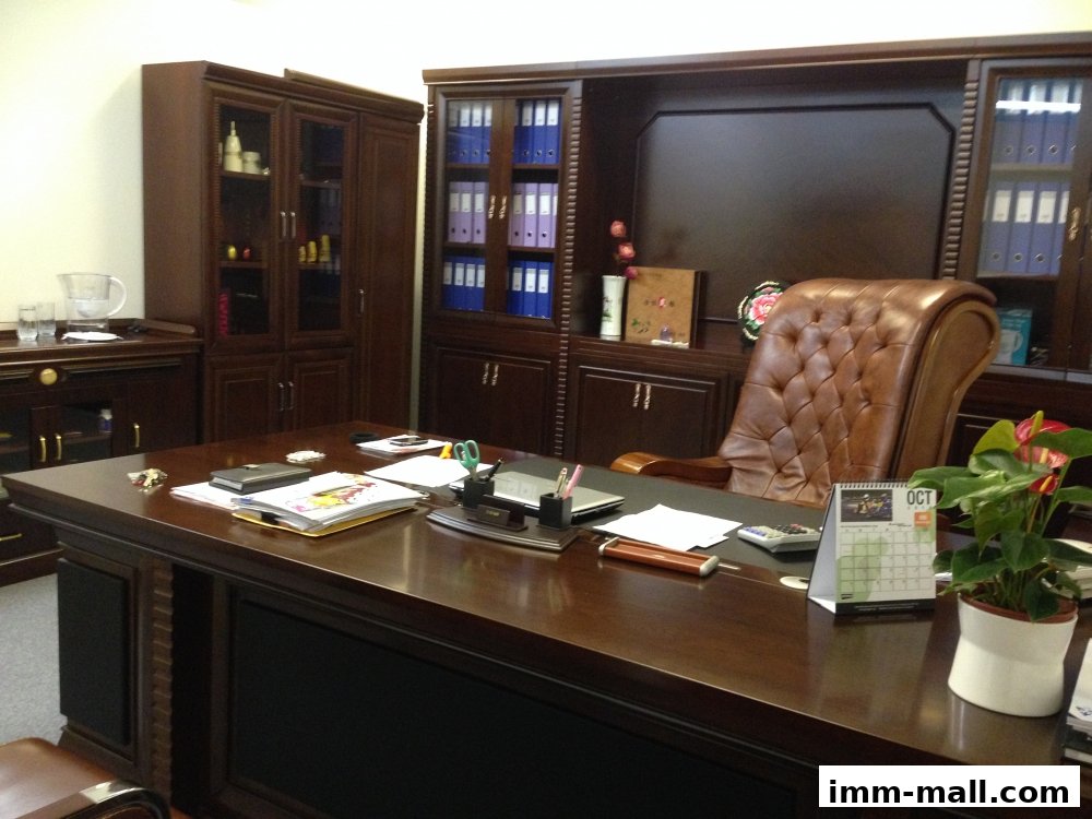 A luxurious executive office with a large wooden desk, leather chair, and built-in cabinetry.
