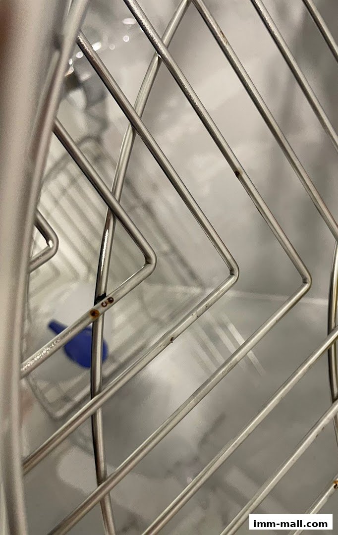 Close-up of a metal rack with a blue object visible in the background.