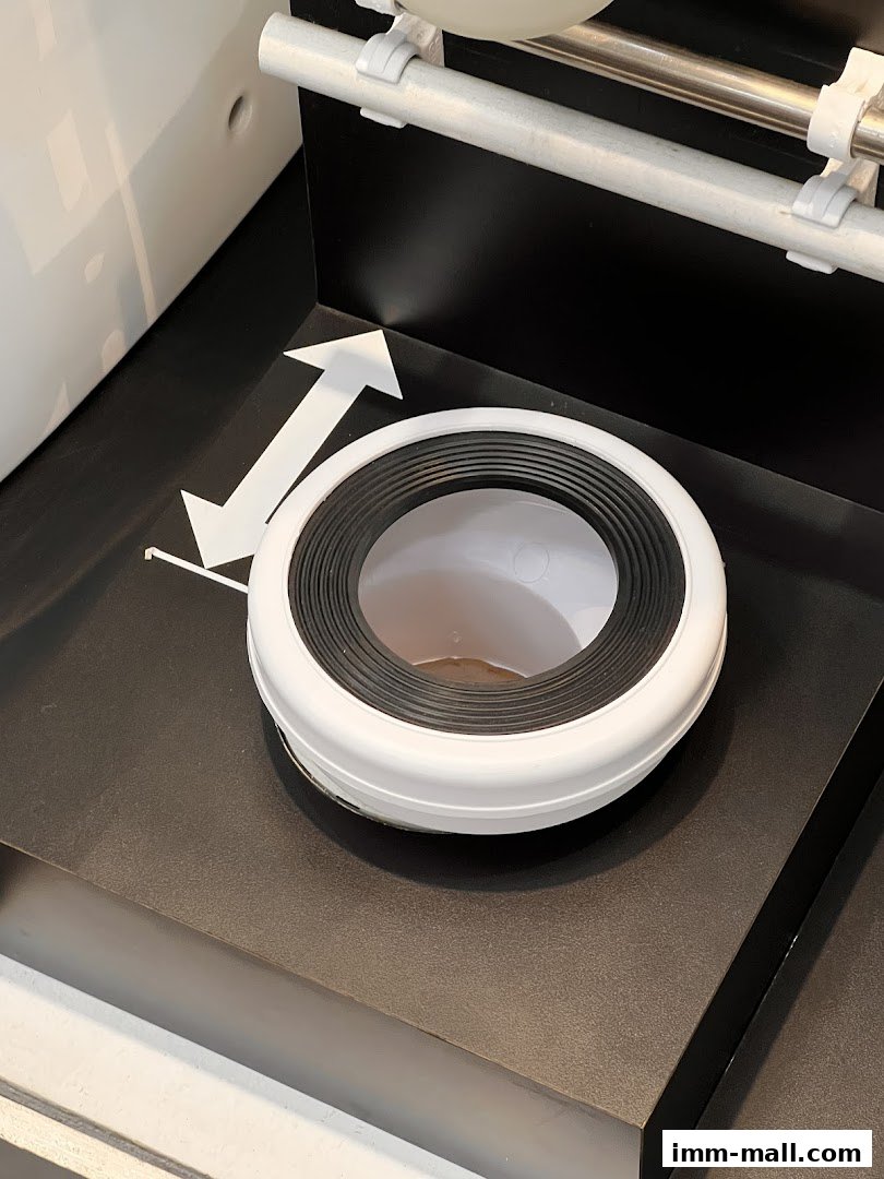 A close-up of a white toilet seat with a black rubber seal on display.