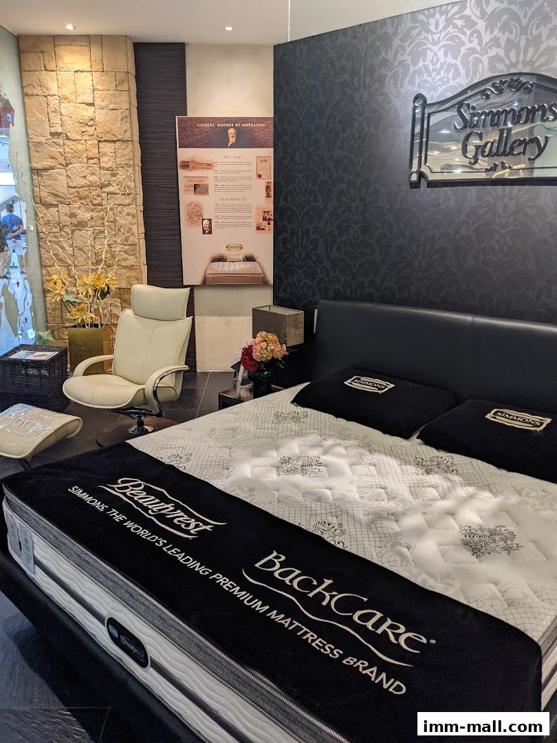 A Simmons Gallery store displays a premium BackCare mattress with pillows and a historical display.