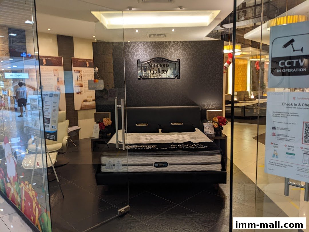 A Simmons Gallery mattress store display featuring a bed and informational posters.