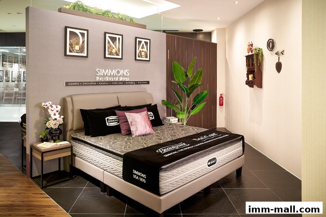 A Simmons Beautyrest mattress display with a headboard, pillows, and decorative items.
