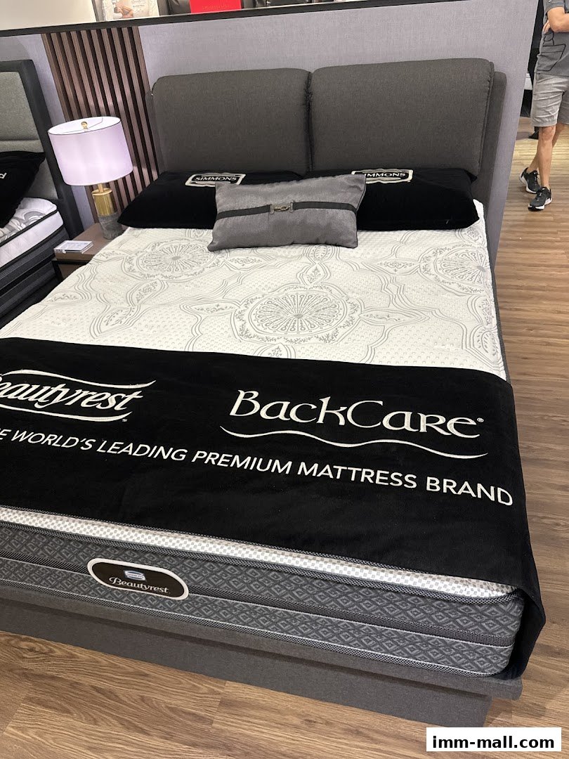 A Simmons Beautyrest BackCare mattress displayed with pillows and a lamp.