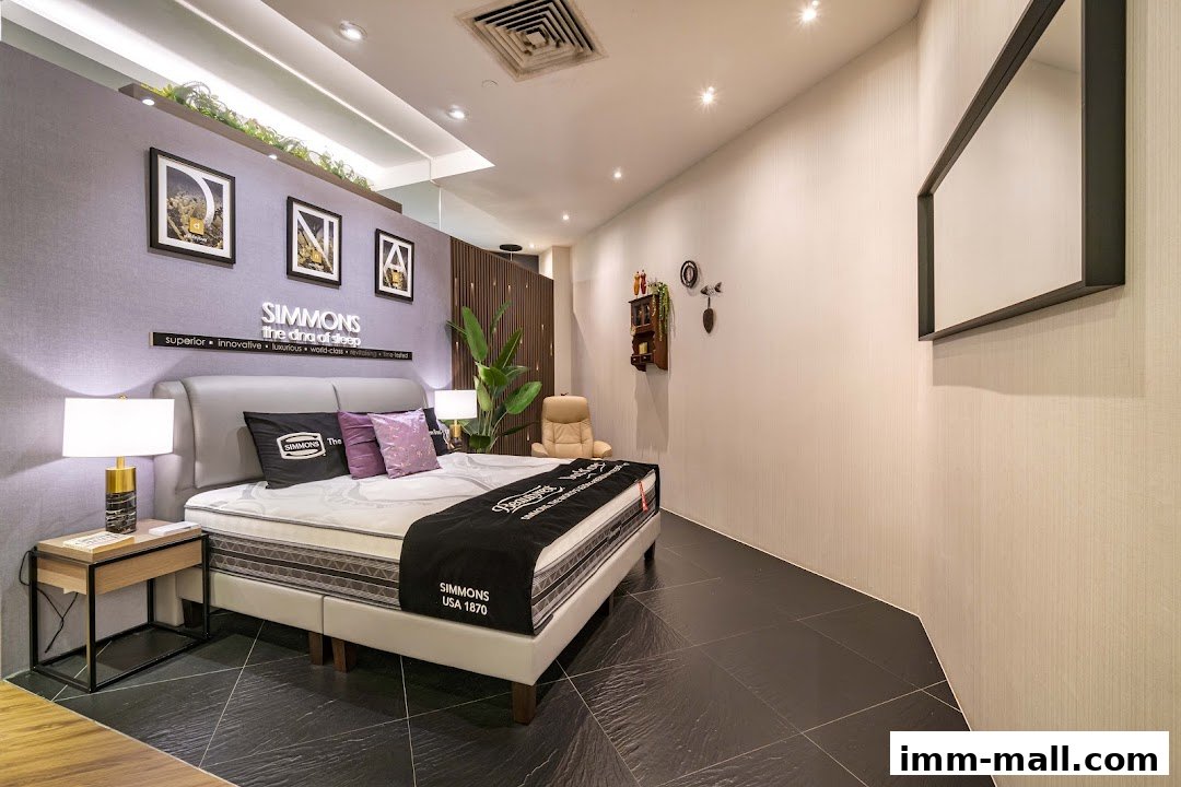 A Simmons mattress display featuring a bed with pillows, lamps, and decorative wall art.