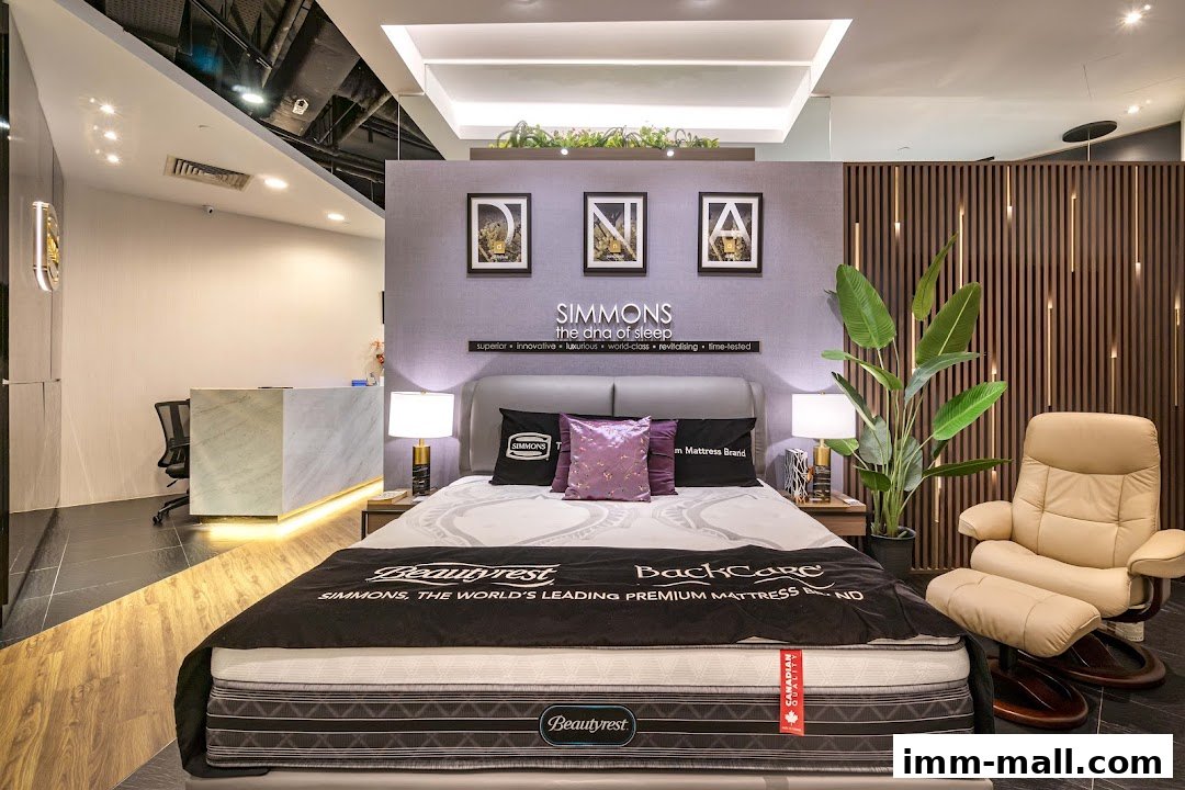 A Simmons mattress showroom featuring a display bed, armchair, and reception desk.
