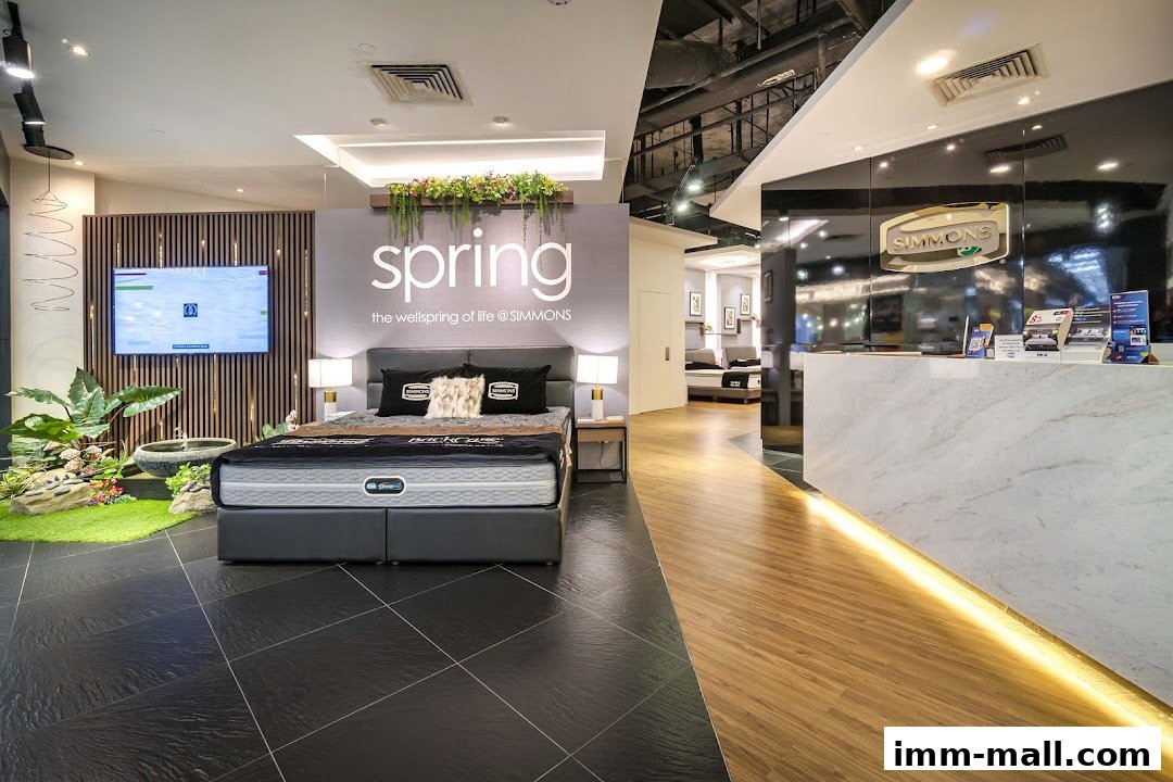 A Simmons mattress showroom featuring a display bed, reception desk, and product information.