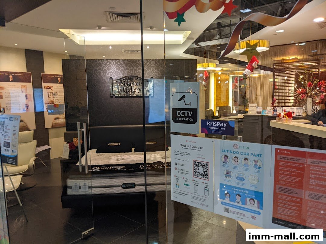 View of the Simmons Gallery shop entrance with a bed display and various informational signs.