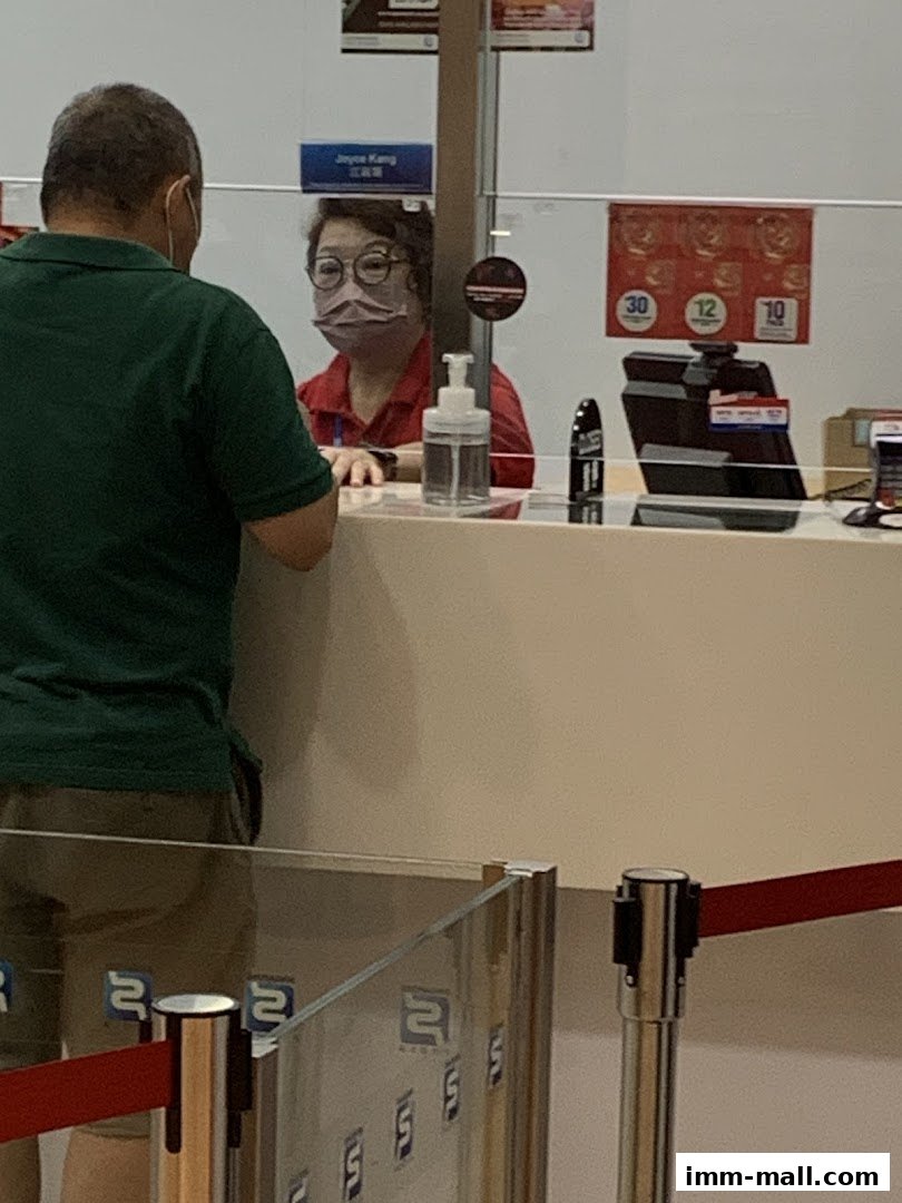 A customer interacts with a staff member behind a counter at Singapore Pools.
