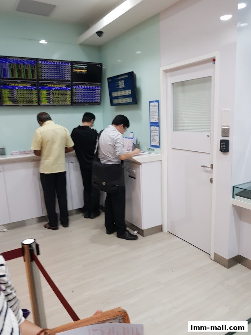 People are queuing at Singapore Pools, with screens displaying information.