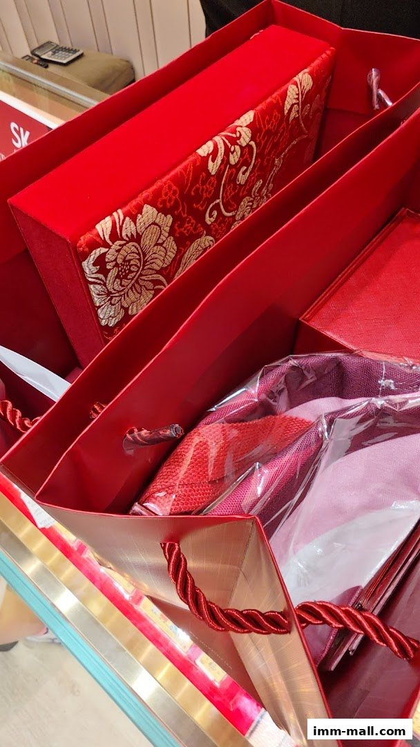 Red shopping bags filled with luxurious red and gold patterned boxes and fabric items.