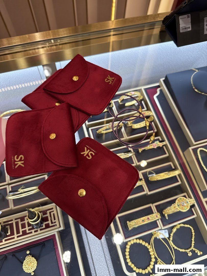 SK Jewellery display case featuring red velvet pouches and various gold bracelets and necklaces.