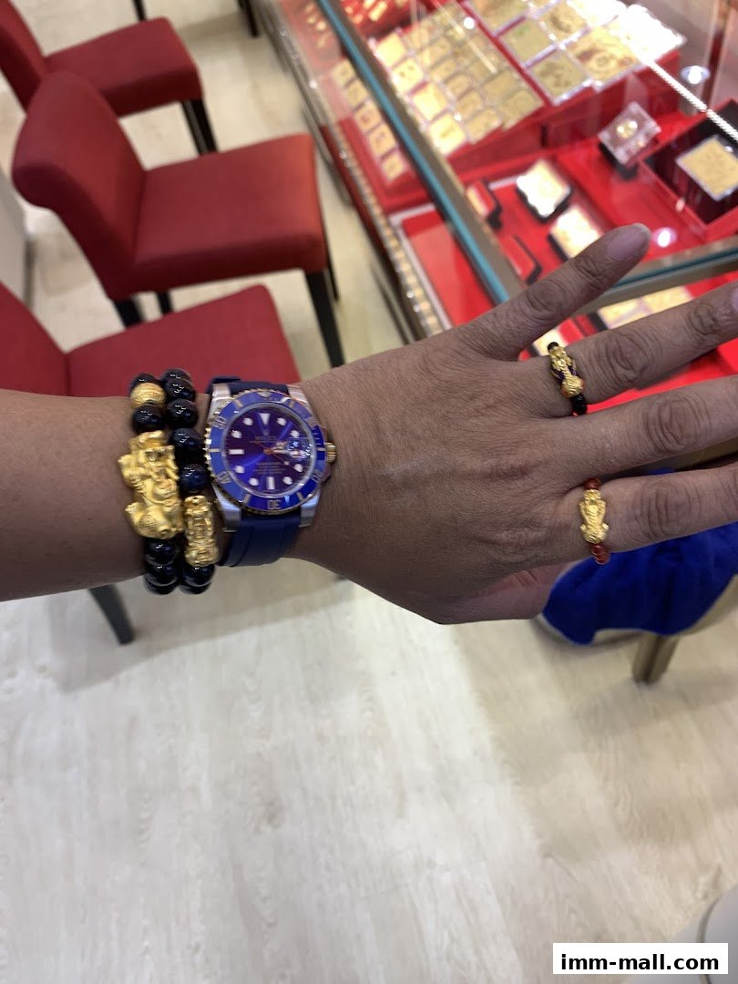 A person wearing a watch and rings with gold charms in a jewelry store.