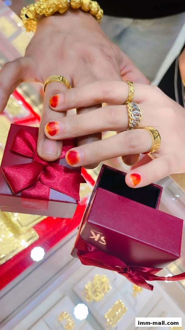Hands adorned with gold rings and a bracelet, holding open jewelry boxes.
