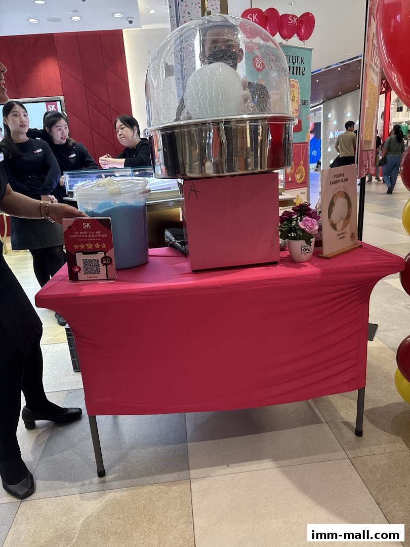 A cotton candy machine is being operated by a vendor at a promotional event.
