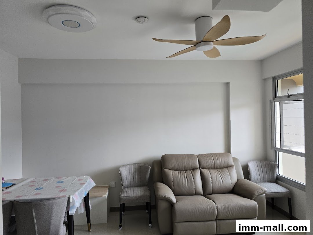 A living room with a sofa, chairs, and a dining table, featuring a ceiling fan and natural light.