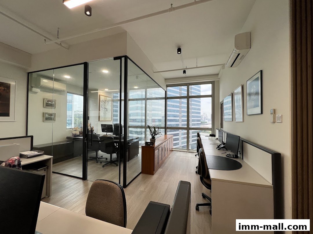 Modern office interior with glass-walled meeting rooms and workstations overlooking a city skyline.