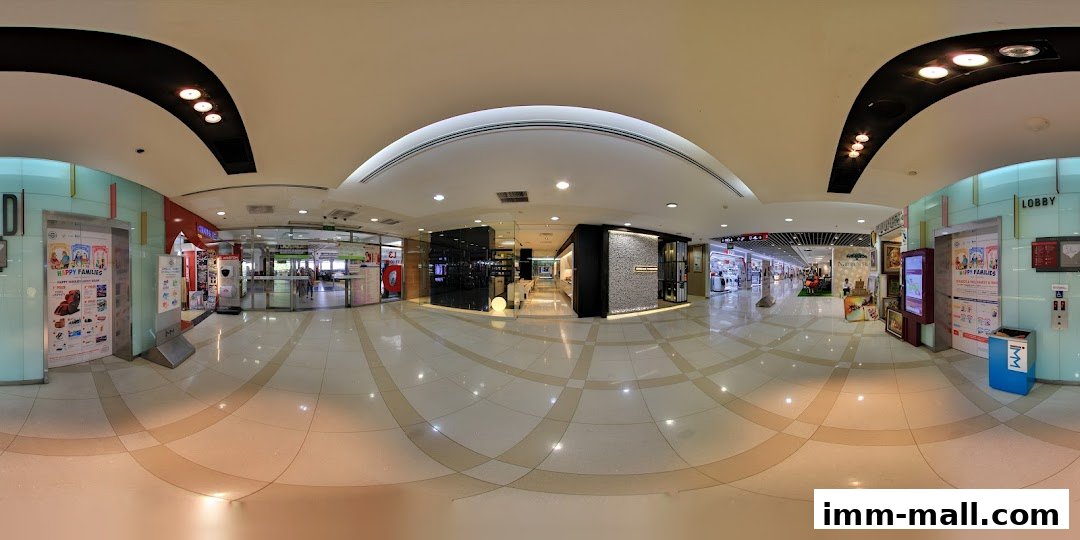 A panoramic view of a clean, modern shopping mall interior with various shops and an elevator.