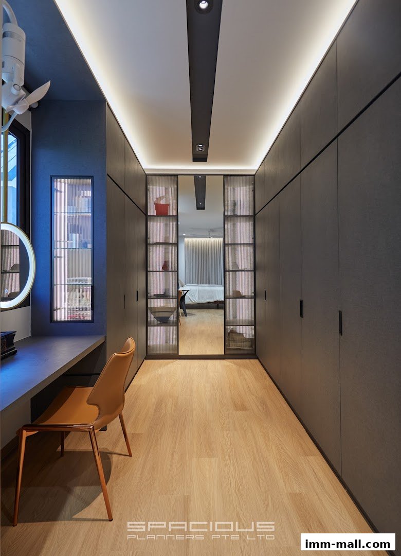 A modern walk-in closet with ample storage, a vanity area, and a mirrored section reflecting a bedroom.