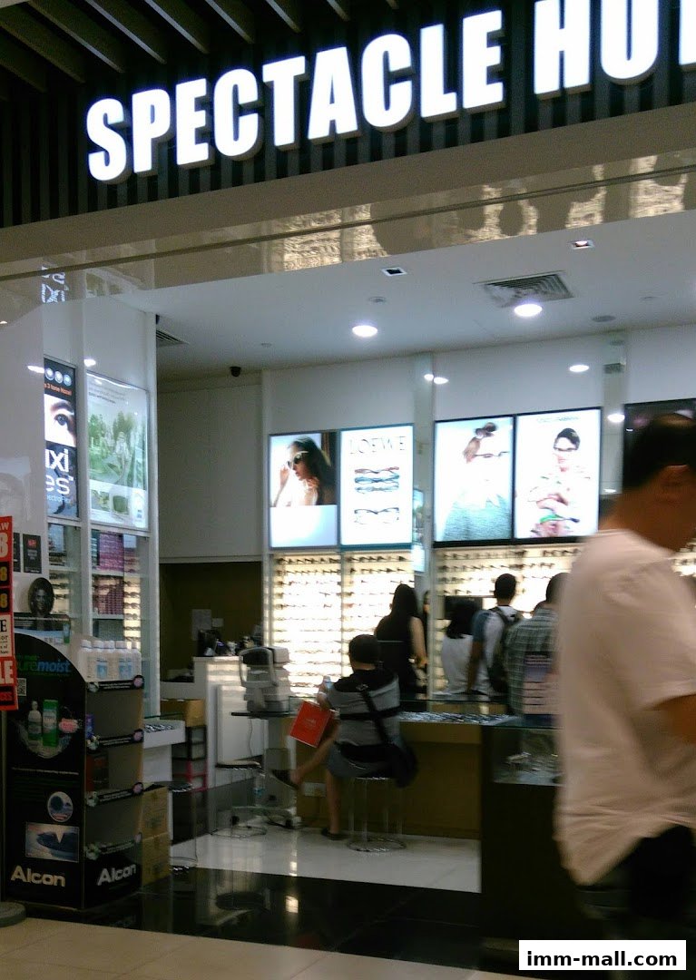 The Spectacle Hut IMM shop front with illuminated signage and displays of eyewear.