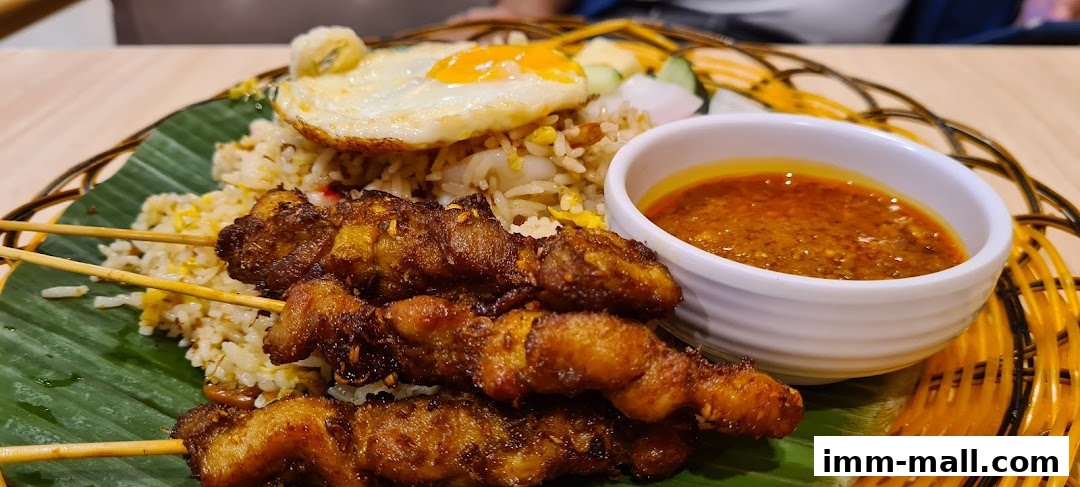 A plate of fried rice with satay skewers, a fried egg, and dipping sauce.