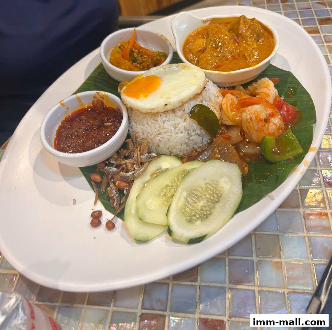 A delicious plate of Nasi Lemak with fried egg, sambal, curry, and prawns.