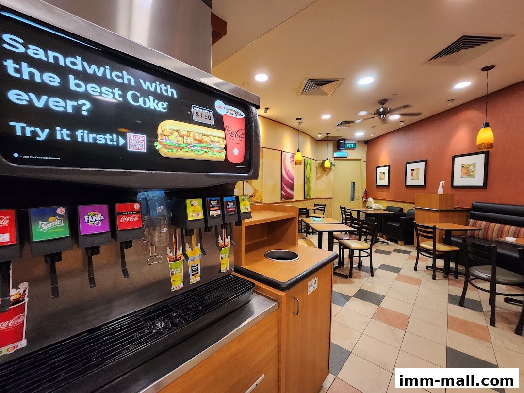 Interior view of a Subway restaurant showing a drink dispenser and seating area.