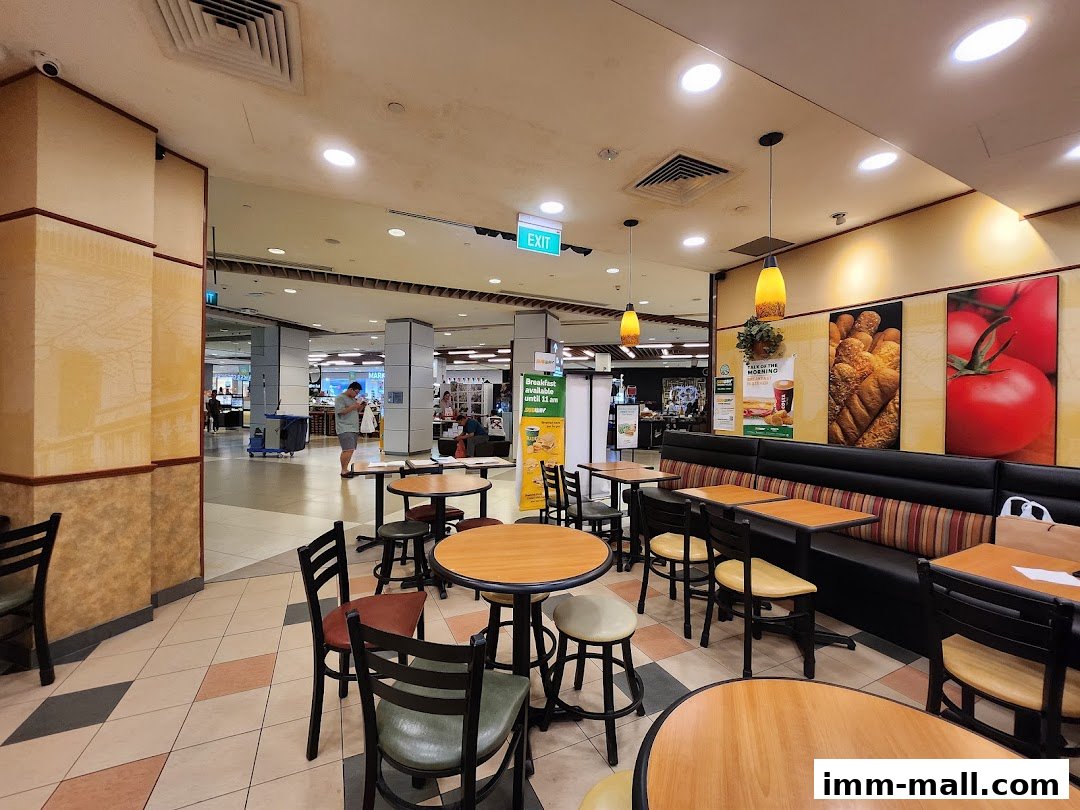 Interior view of a Subway restaurant with seating areas and a glimpse of the mall walkway.