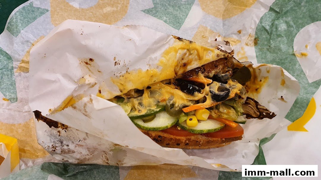 A close-up of a Subway sandwich with melted cheese and fresh vegetables.