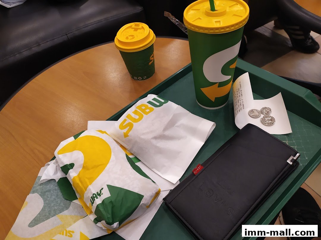 Subway sandwiches and drinks on a tray with a wallet and coins.