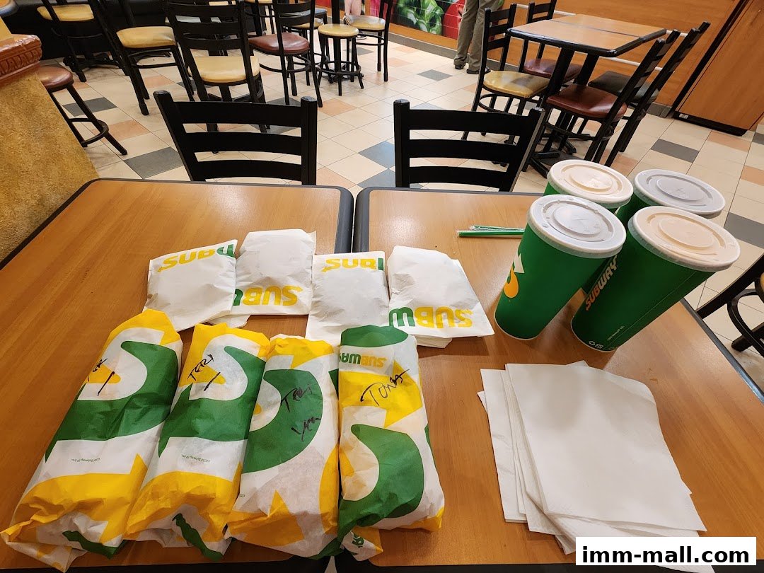 A table at Subway with several wrapped sandwiches and drinks, ready for takeaway.