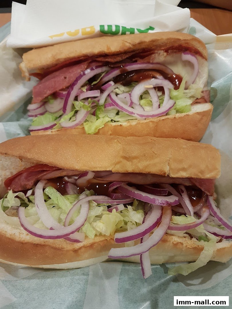 Two freshly made Subway sandwiches with lettuce, onions, and sauce.