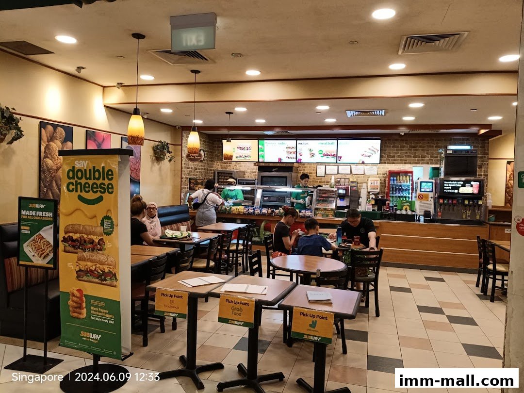 Interior view of a Subway restaurant with customers dining and staff behind the counter.