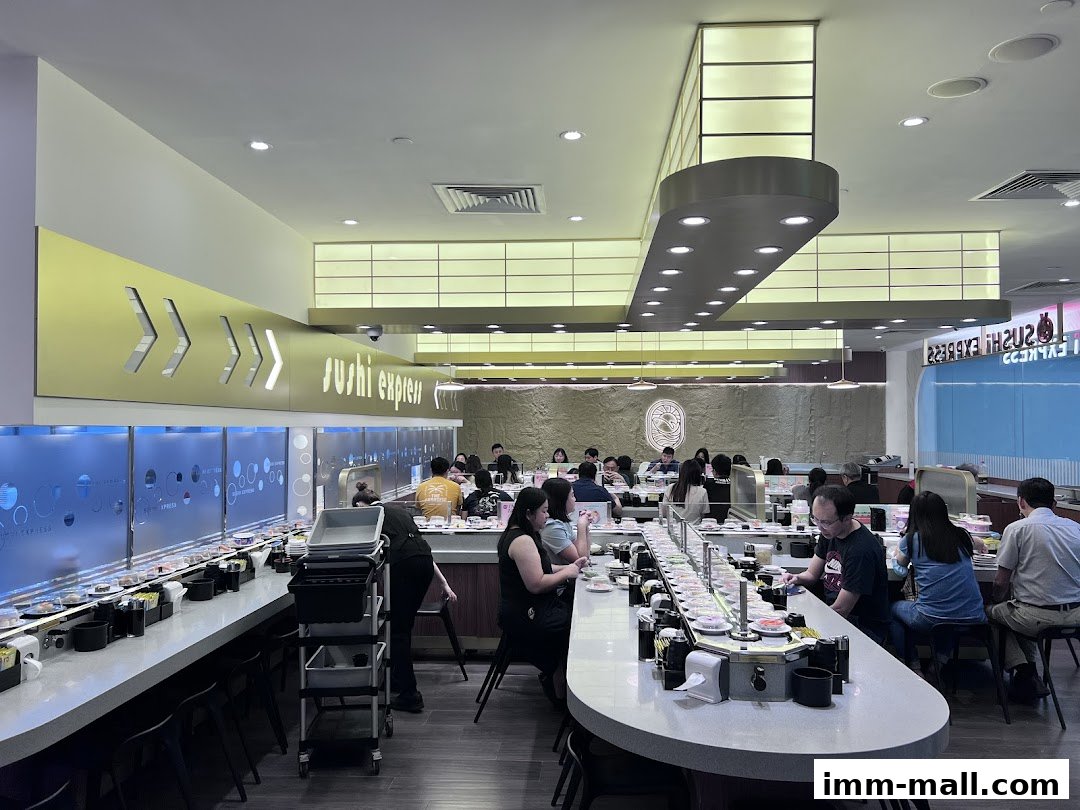 Interior of a busy Sushi Express restaurant with customers seated at a conveyor belt sushi bar.