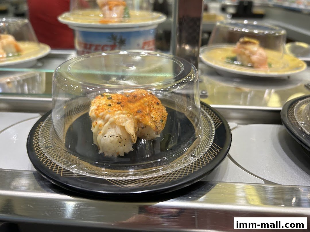 Close-up of a conveyor belt sushi dish with a covered piece of sushi.