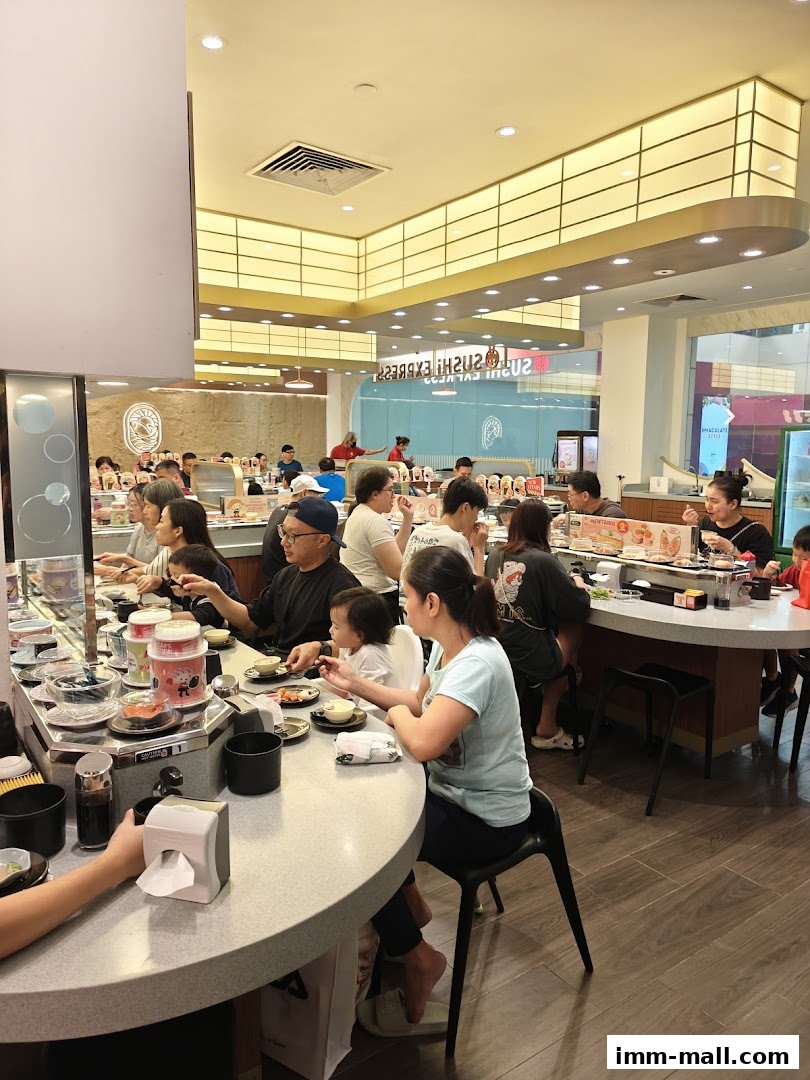 People dining at Sushi Express, a conveyor belt sushi restaurant with a bright interior.