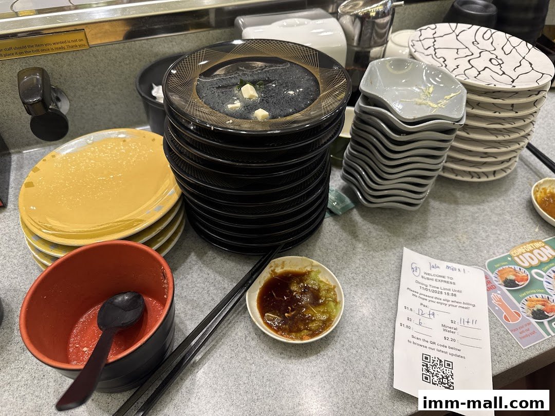 A table at Sushi Express with stacked plates, dipping sauce, and a receipt.