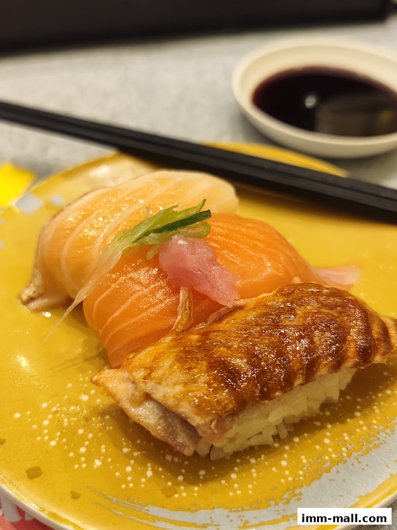 A close-up of delicious salmon sushi and grilled eel sushi on a yellow plate with chopsticks and soy sauce.