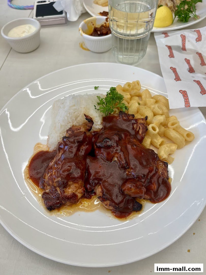 A plate of BBQ chicken with rice and macaroni and cheese, served with a drink.
