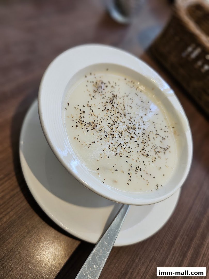 A close-up shot of a creamy soup topped with black pepper, served in a white bowl.