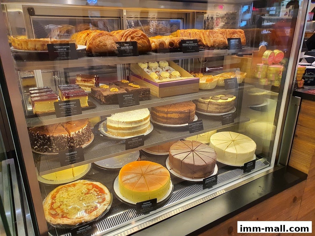 A display case filled with various cakes, pastries, and a pizza.