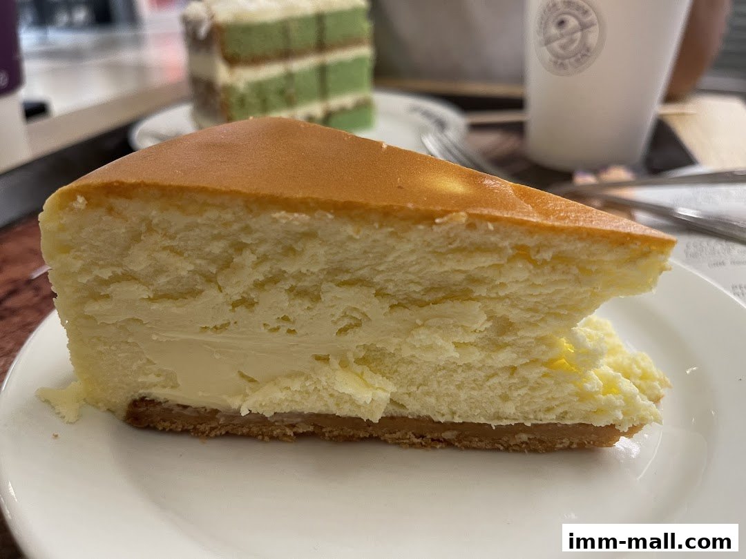 A slice of creamy cheesecake with a graham cracker crust on a white plate.