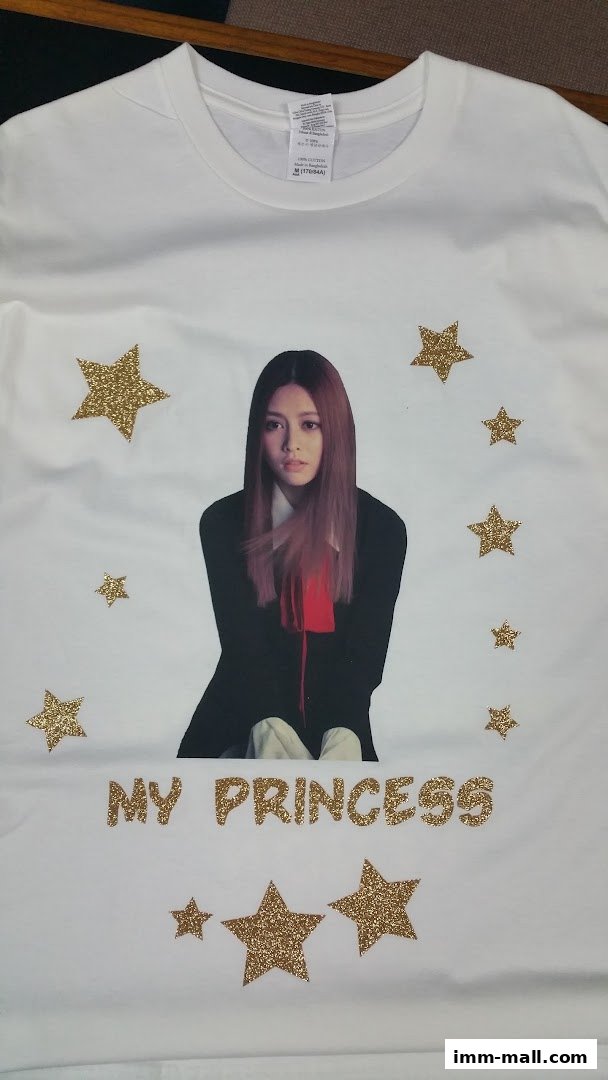 A white t-shirt with a printed image of a young woman and gold glitter stars.