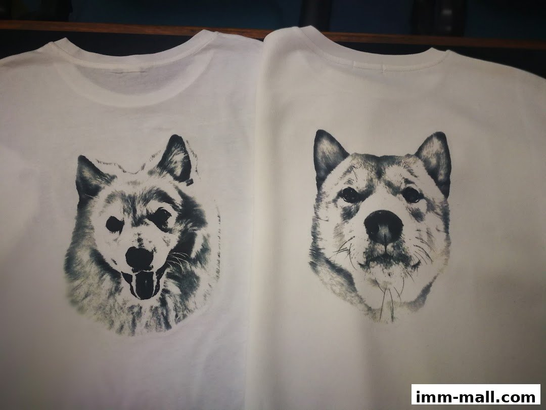 Two white t-shirts featuring realistic black and white dog portraits.