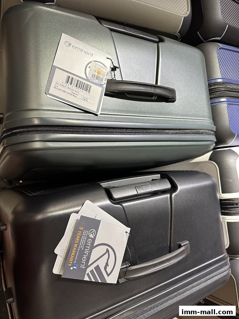 Close-up view of two large, durable suitcases from the Eminent brand, one grey and one black.