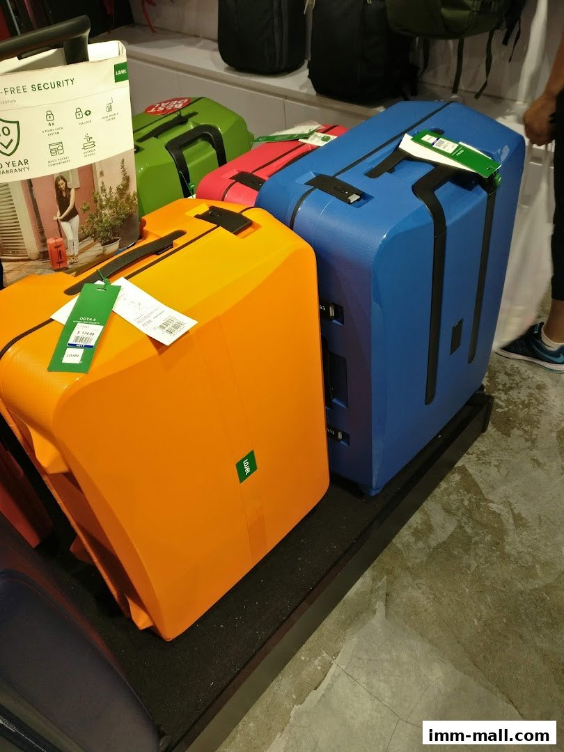 Colorful suitcases displayed in a retail store, featuring a promotional sign.